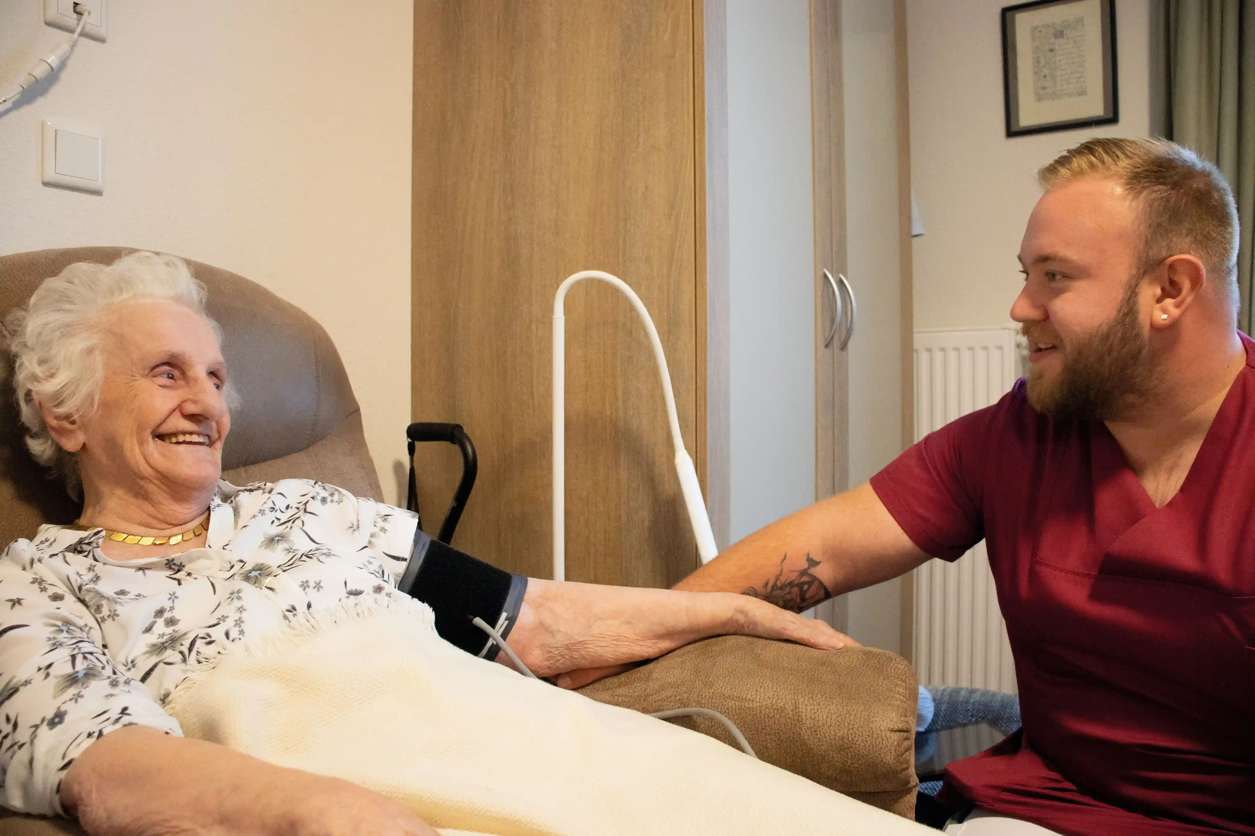 Seniorin wird im Pflegeheim von einem freundlichen Pfleger fürsorglich betreut und umsorgt.