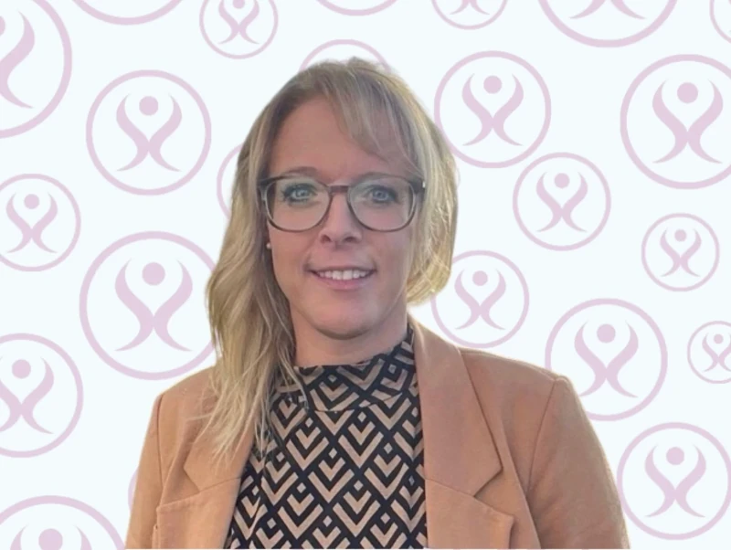 Frau mit Brille und Blazer vor modernem Firmenlogo-Hintergrund für Business-Portrait.